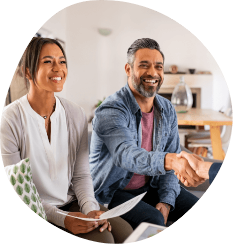 Man shaking hands with someone while sitting next to woman