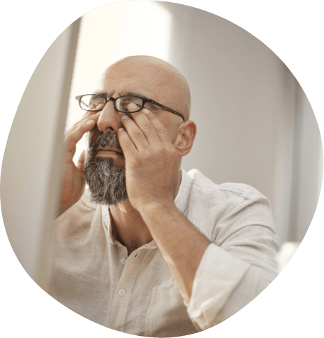 Man with glasses and beard rubbing his eyes
