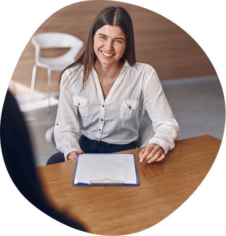Smiling woman sitting at desk with clipboard