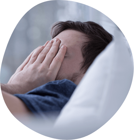Man lying in bed rubbing his eyes
