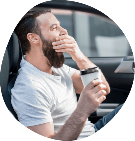 Man driving while yawning and holding coffee cup