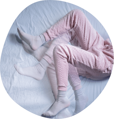 Legs in pink pajama pants kicking while laying in bed