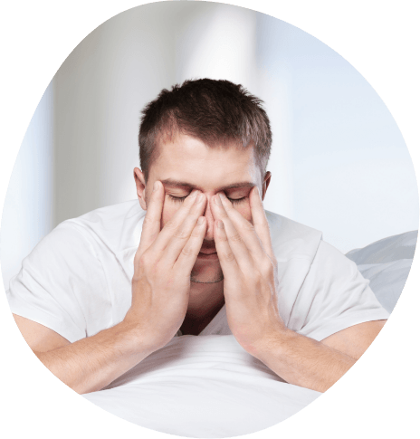 Man sitting in bed rubbing his eyes