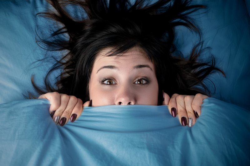woman scared and hiding under the covers